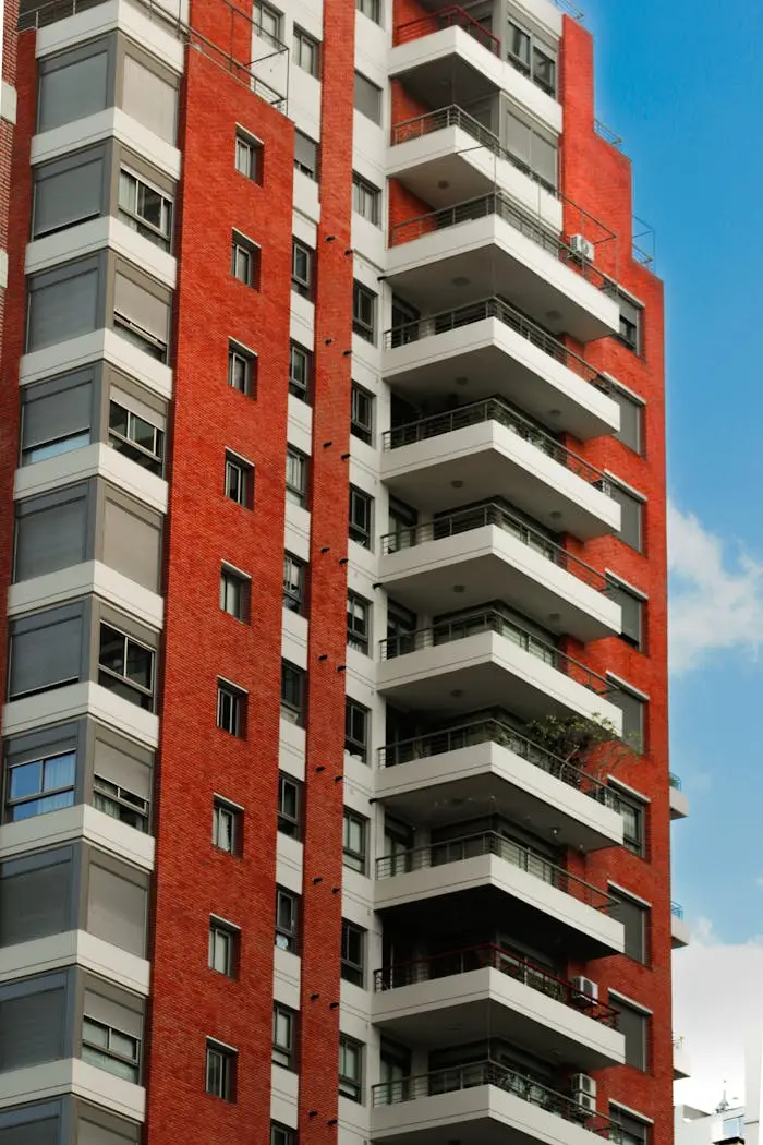 Services High-rise red brick apartment building with balconies in an urban setting.